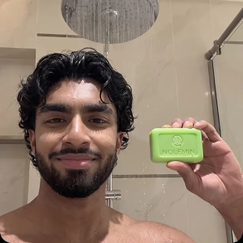 Cliente mostrando una barra de jabón Nolemin en la ducha